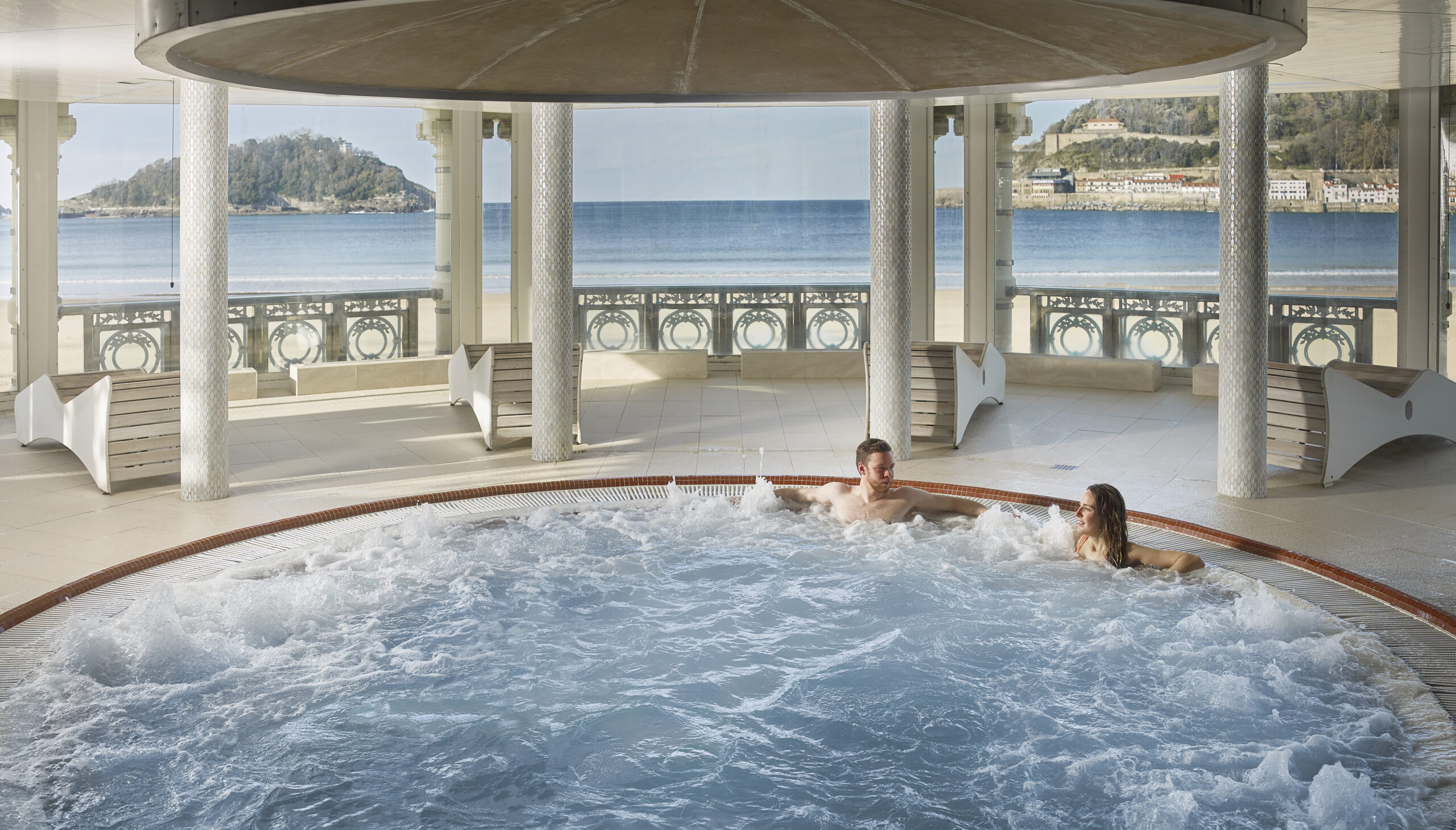 Interior del circuito de talasoterapia de La Perla, con piscina de agua marina y columnas de mosaico