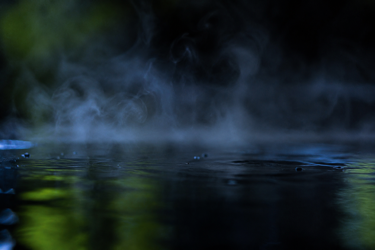 Primer plano del vapor subiendo de la superficie oscura del agua termal