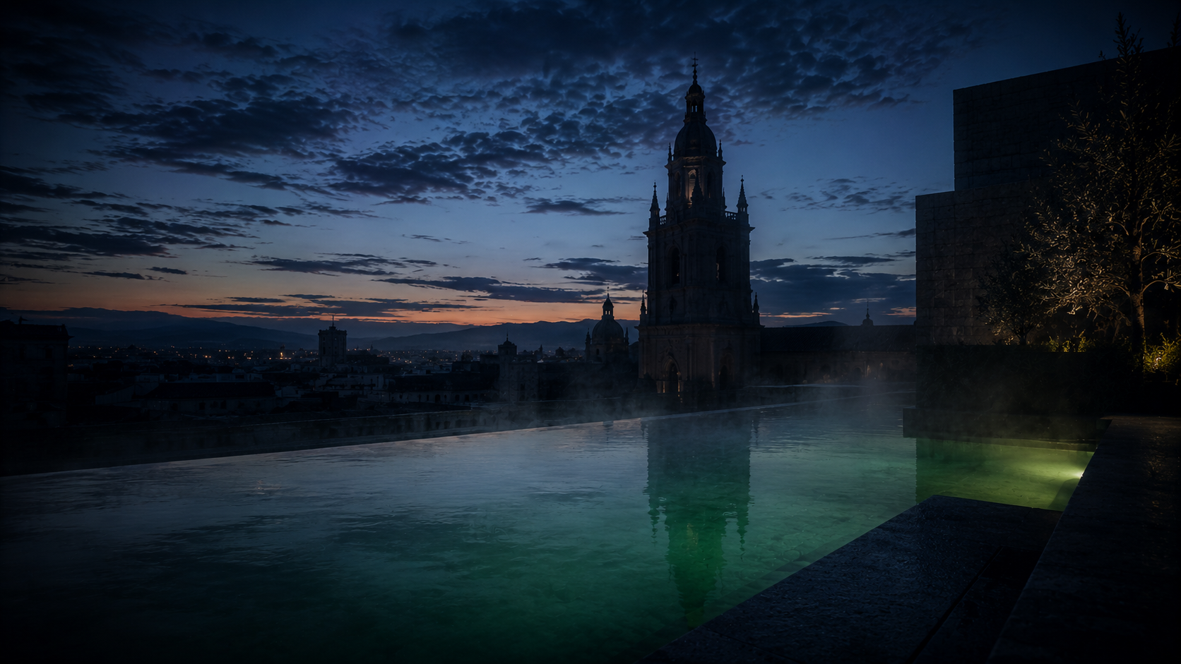 Baño infinito en una azotea a la hora azul con la silueta de una torre de catedral al fondo
