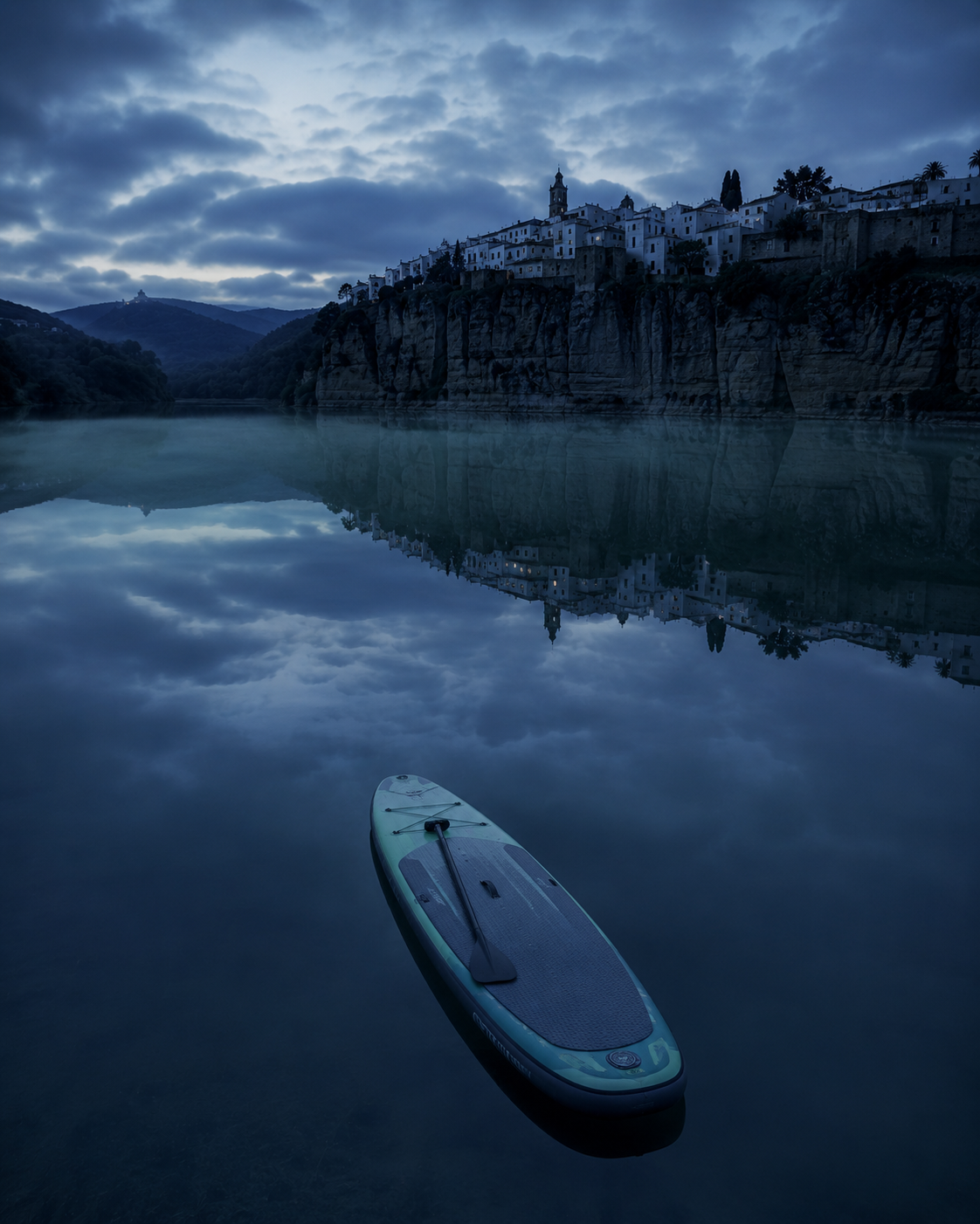 Tabla de paddle surf sola sobre el agua en calma del embalse de Arcos al amanecer