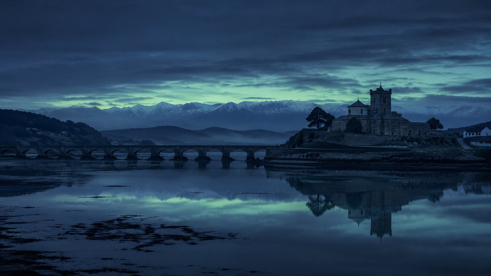 El estuario de San Vicente de la Barquera con marea alta y los Picos de Europa nevados al fondo a la hora azul