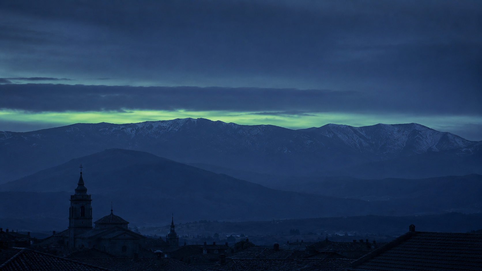 La sierra de Guadarrama al anochecer azul, con el perfil de las montañas sobre los tejados del Real Sitio