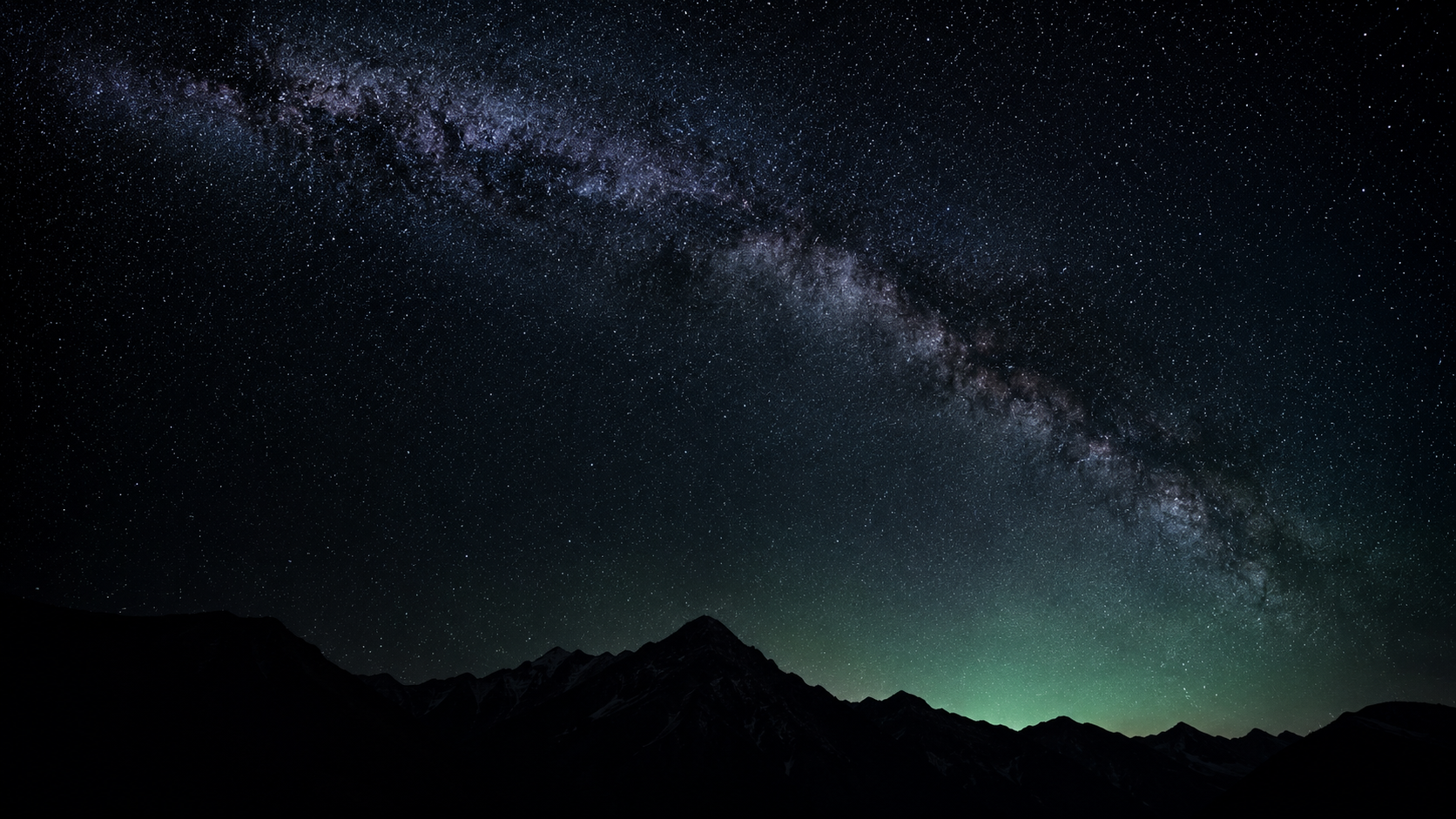 La Vía Láctea sobre una silueta de montañas oscuras, cielo estrellado sin contaminación lumínica