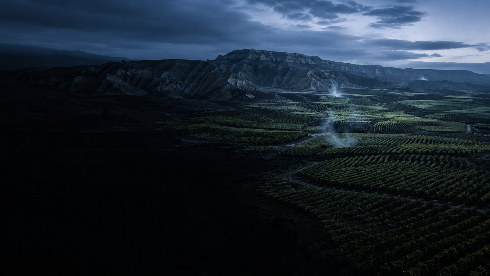 Valle riojano con viñedos y vapor de agua termal a la hora azul, sin nadie a la vista