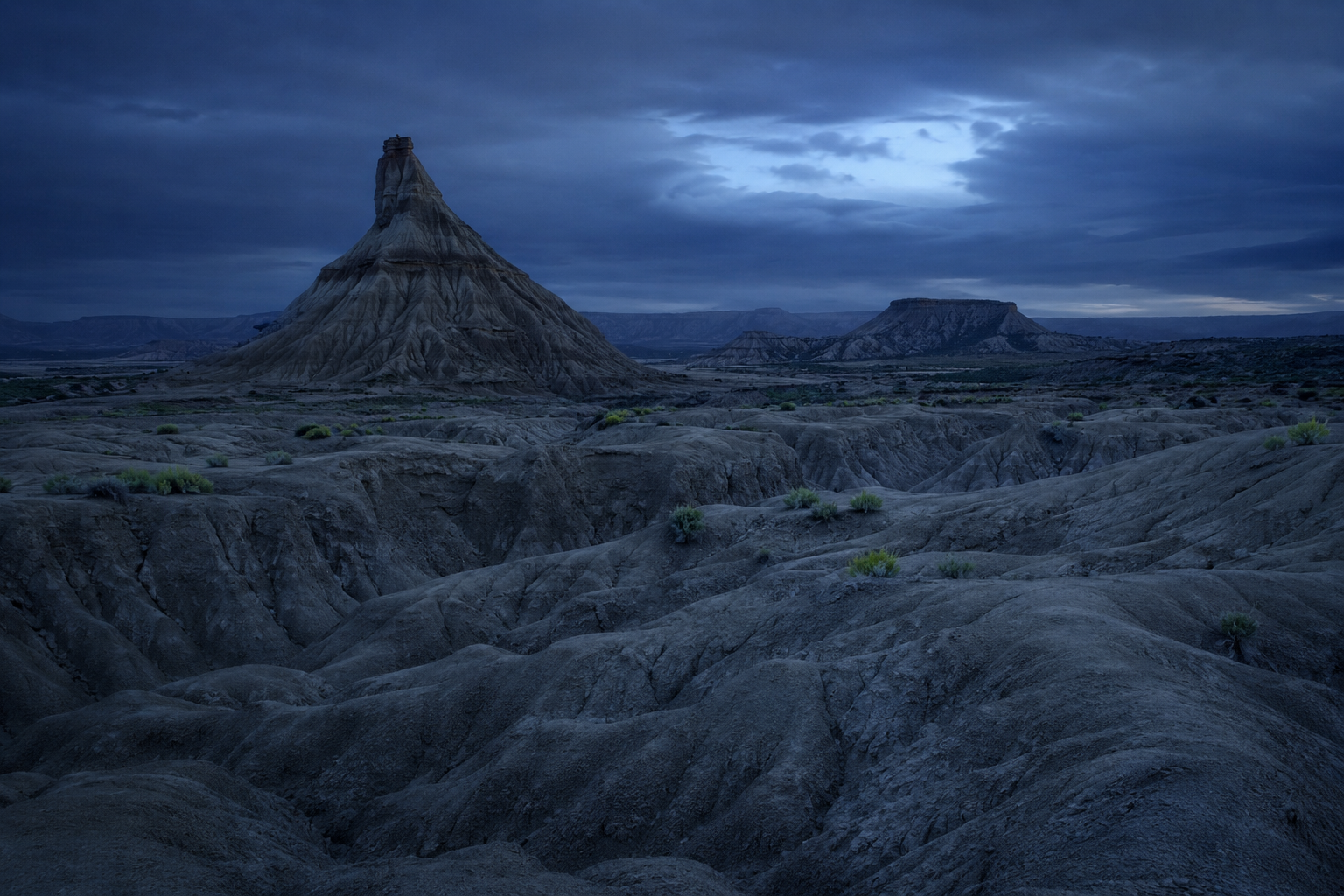 Paisaje semidesértico de las Bardenas Reales al atardecer, tierra ocre y cárcavas, a la hora azul