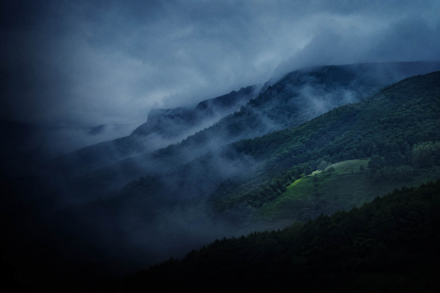 Parque Natural del Gorbea con bruma entre laderas verdes a la hora azul, sin nadie a la vista