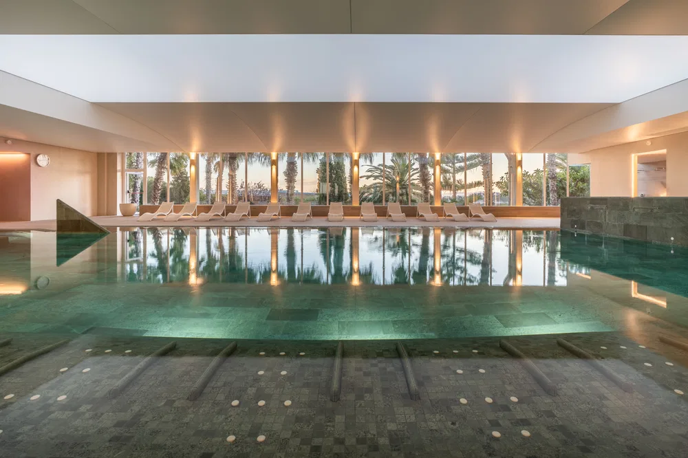 Piscina interior de agua de mar de Palasiet con la cristalera abierta a las palmeras y al Mediterráneo