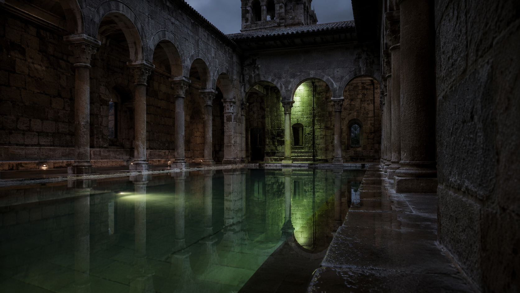 Piscina termal iluminada en un claustro de piedra a la hora azul, con el agua en calma y sin nadie a la vista