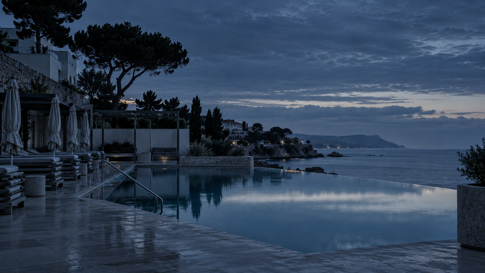 Piscina exterior vacía de un hotel frente al mar del Maresme a la hora azul, con las tumbonas recogidas